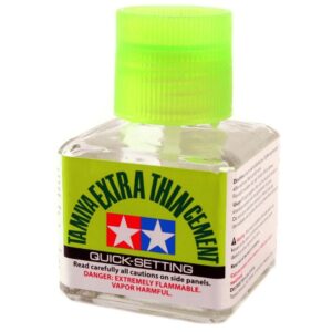 Tamiya Extra Thin Cement bottle with quick-setting formula and safety warnings for model builders.